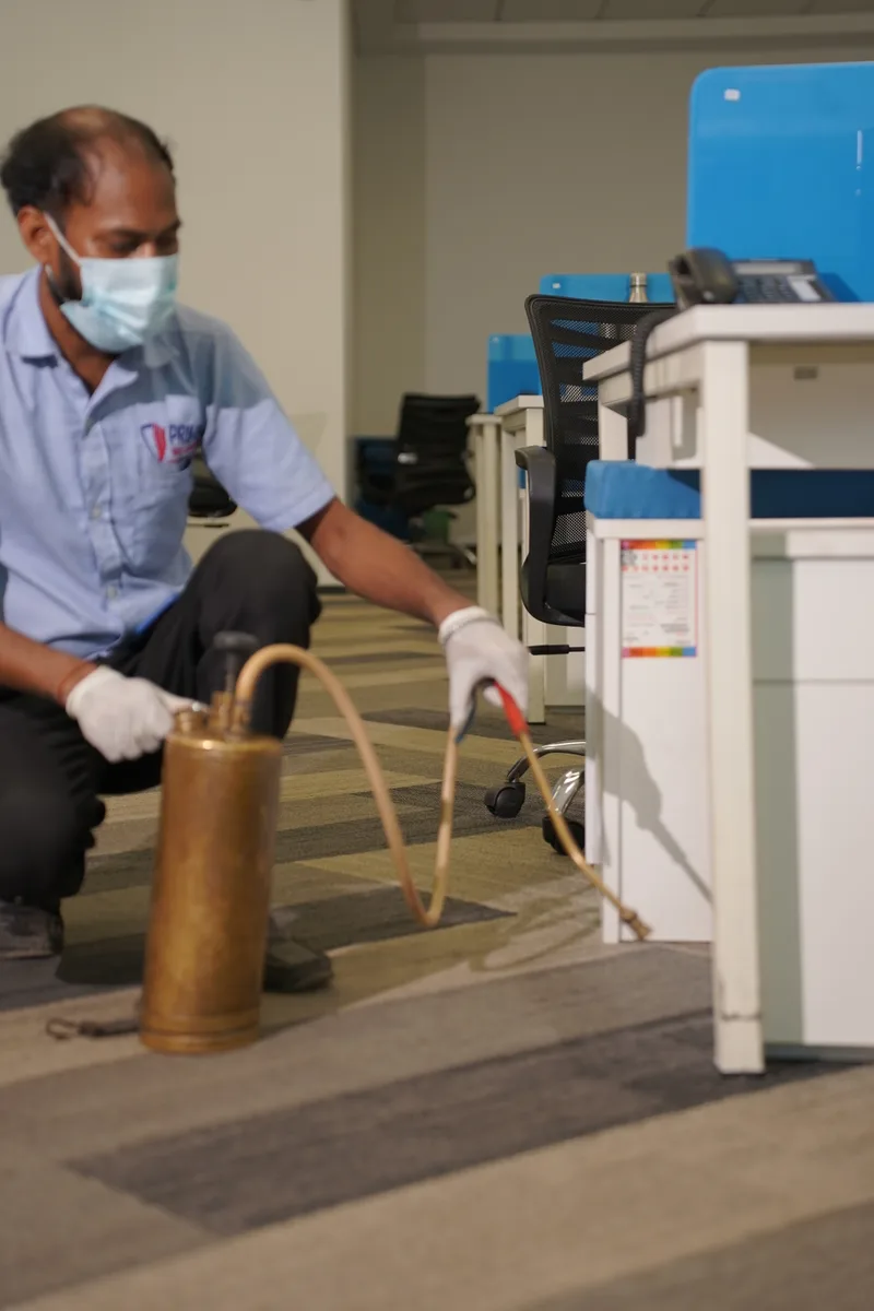 Technician treating skirting under office furniture